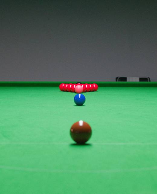 Ein Snookertisch mit vollständig aufgebautem Dreieck roter Kugeln hinten und farbigen Kugeln in ihrer Startposition entlang der Mittelachse.